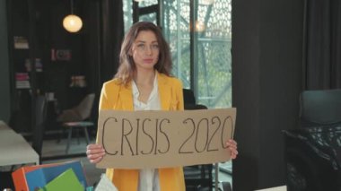 NEW YORK - 28 Mart 2020: Kurumsal ofis odasında işten çıkarıldıktan sonra kriz 2020 afişi gösteren genç bir kadının portresi. İşsizlik Kurumu.