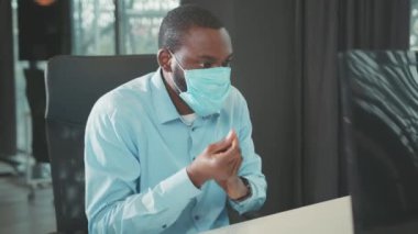 Genç Afro-Amerikalı iş adamı antiseptik kullanıyor. Dezenfekte için elleri kullanıyor. Bilgisayar koronavirüsünde işe başlıyor.