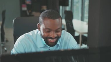 Olumlu gülümseyen Afrikalı Amerikalı adam maskeyi çıkarıyor modern ofis programcılarında bilgisayar kullanıyor ekran işadamı Coronavirus 'a bakıyor yavaş çekimde kapat