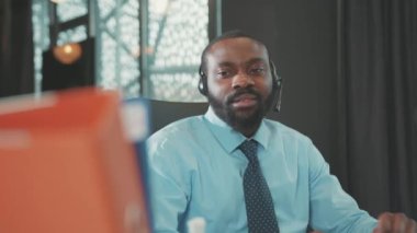 Kulaklık kullanan Afrikalı Amerikalı bir adam Coronavirus krizi nedeniyle kovulan kişisel eşyalara bakıyor. İşsiz iş dünyası ağır çekim iş gücü ekonomisi.