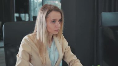 Portre, ofis içinde çalışan, masaüstü bilgisayar masasında oturan, konsantre olmuş genç, sarışın bir kadın. Siyah iç mekan. İş adamları. Çalışma Alanı.