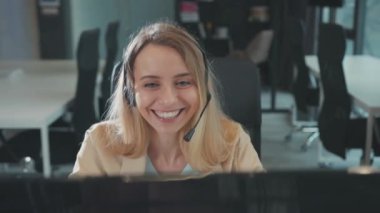 Kulaklıklı sarışın genç bir iş kadınının masaüstü bilgisayarında online web kameralı konferans görüşmesi yapması, online kurs uzaklığı sohbetinde el kol hareketi yapması. İletişim.