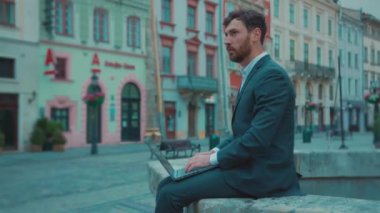 İşsiz, beyaz, sakallı bir adam, dışarıda boş bir sokakta duran taşınabilir dizüstü bilgisayarla internette iş arıyor. Şehir karantinada. Ticari işler kapanıyor..