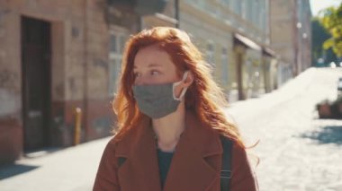 Beyaz saçlı genç bir kadın yüz maskesi çıkartıyor. Karantinanın tadını çıkarıyor. Kameraya gülümsüyor. Açık hava portresi. Salgın sona erdi. Sağlık Hizmetleri.