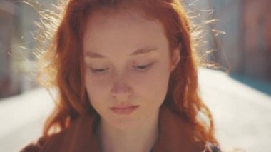 Eşsiz, güzel, kızıl saçlı genç, beyaz bir kadının portresi. Güneşli bir havada, sokakta kendinden çok emin görünüyor. Çekici gençlik. Kentliler.