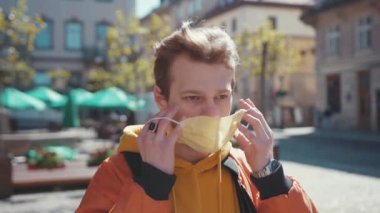 Sarışın, virüs önleme maskesi takan öğrenci genç adam güneşli bir günde dışarıda dikilmeye hazır. Şehir yaşam tarzı ve sağlık hizmetleri. Salgın. Coronavirüs.