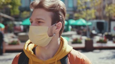 Yüzüne maske takan genç ve mutlu bir adamın portresi temiz hava soluyor ve nihayet karantinanın sona ermesini kutluyor. Coronavirüs.