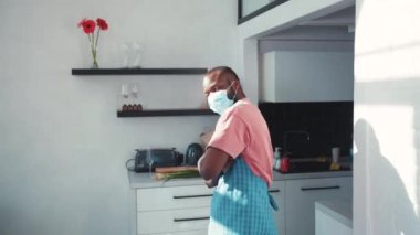 Yüzü maskeli komik siyah bir adam mutfakta komik bir dansla vücudunu hareket ettiriyor, bir tabak tutuyor ve saflığını kontrol ediyor. Eğlence, eğlence. Çılgın şef konsepti.