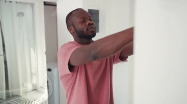 Genç Afrikalı Amerikalı adam aynanın önüne yeşil ceket giyer. İş için giyinen şık bir adam evden çıkıyor. Sıradan insanlar. Yaşam tarzı. Daire.