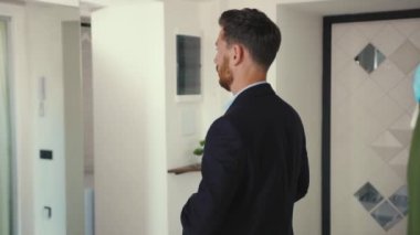 Maskeli yakışıklı işadamı aynaya bakıyor ve takım elbise giyiyor. Git ev güvenliği için çalış. Profesyonel apartman dairesi kordemik ağır çekim.