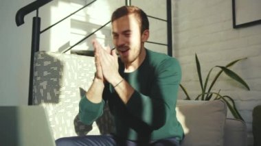 Bilgisayarı kullanan yakışıklı adam evde çalışırken mutlu oluyor. Bilgisayarda gülümsüyor, ekranda yazı yazıyor ve yavaş çekimde serbest girişimci teknolojisine bakıyor.