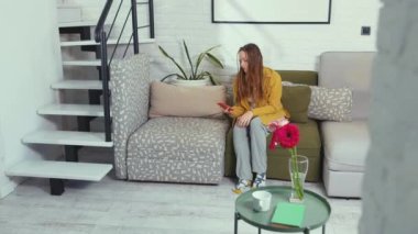 NEW YORK - 5 Mart 2020: Telefon etmek için acele eden ve akıllı telefona bakan bir kadın evde oturan güzel, üzgün, rutin çekici teknolojiyi yavaş çekimde kapatıyor.