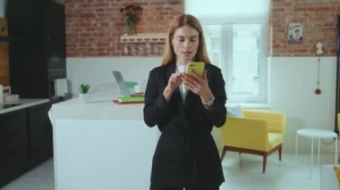 Gülümseyen genç iş kadını iyi haberler alan telefonu kullanıyor. Ev ofisinin internet portresi teknolojisi işyerinde mutlu oldu.