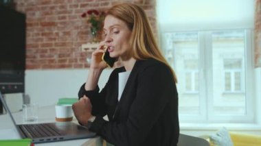 Güzel, ciddi, genç iş kadını akıllı telefondan konuşuyor. Ev bilgisayarını kullan. Başarılı bağlantı teknolojisi iletişimi, yavaş çekimde internet.