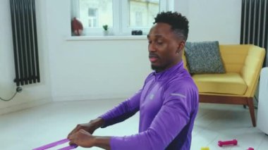 Afrikalı Amerikalı adam spor kıyafetleri spor antrenmanında spor yaparken spor bantları kullanarak spor yaparken yavaş çekimde online antrenörle egzersiz yapıyor.