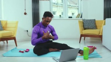 Antrenör Afrikalı Amerikalı adam çevrimiçi konuşuyor ve karantina antrenörü spor spor salonu spor salonu ağır çekim egzersiz sırasında dizüstü bilgisayar ekipmanlarıyla uzaktan iletişim kuruyor.