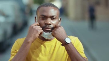 Sokak şehrinde koruyucu maske takan Afro-Amerikan portresi. Karantina sonrası Coronavirus covid-19 direniş koronası yavaş çekim.