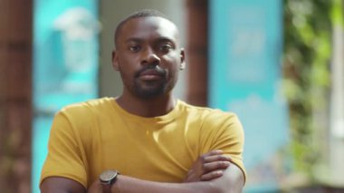 Afro-Amerikan portresi. Sokak şehrindeki kamera standına bak. Neşeli, güneşli, mutlu, yakışıklı, kendine güvenen, yavaş çekim.