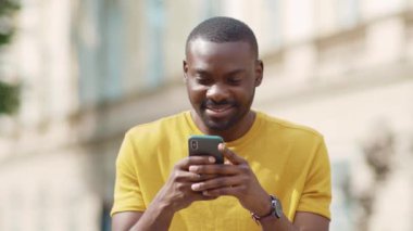 Gülümseyen Afrikalı Amerikalı çekici bir adam telefon kulübesini güneş batımında kullanıyor cep telefonu moda interneti teknolojinin dışında yavaş çekim