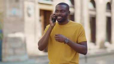 Yakışıklı Afro-Amerikalı çekici adam, telefon kulübesinde konuşuyor, gülümsüyor, günbatımı, cep telefonu moda interneti teknolojinin dışında, yavaş çekim.