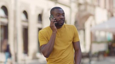 Komik Afrikalı Amerikalı çekici adam, telefon kulübesinde konuşuyor, gülümsüyor, günbatımı, cep telefonu moda interneti, teknolojinin dışında, yavaş çekim.