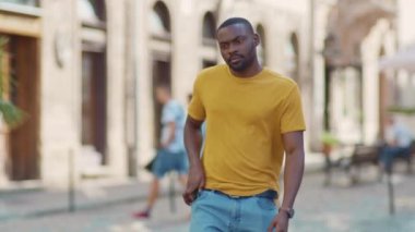 Genç Afro-Amerikalı çekici adam telefona bakıp gülümsüyor. Gün batımında mutlu bir yürüyüş. Cep telefonu moda interneti.