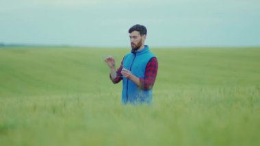 Sahada çalışan genç çiftçiyi kapatın. Şeffaf cihaz kullanın. Hologram üzerinde tıklayarak ve kaydırarak.