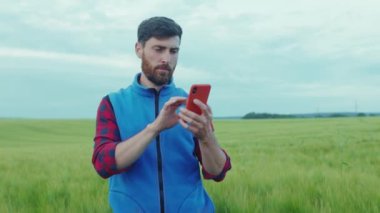 Kapatın genç çiftçi yeşil alanda duruyor cep telefonu tarım endüstrisi beslenme organik tarım adam çiftçiler yavaş çekim kapatın