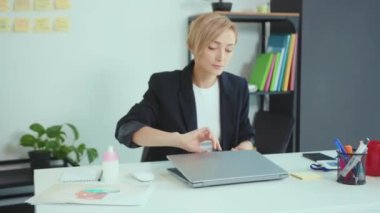 Ofiste çalışan genç ve güzel bir kadın dizüstü bilgisayarda çalışıyor gülümsüyor iş yerinde bilgisayar işi ağır çekimde.