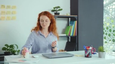 Hoş bir genç kadın dizüstü bilgisayar kullanmadan önce sprey sıkarak ellerini ovuşturuyor ofis ofis Corona virüs koruma kavramını yavaş çekimde kullanıyor.