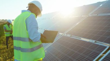 Çalışan mühendis dizüstü bilgisayar kullanıyor. Güneş pillerine dokun. Güneş ışığı teknolojisinde yenilenebilir enerji işçisi.