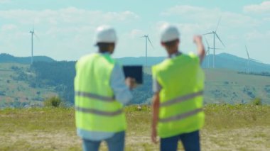 Yakın çekim teknisyenleri, tarlalarda yel değirmenlerinin yanındaki dizüstü bilgisayar standını kullanırlar. İş birliği, rüzgar enerjisi tarım teknisyenleri yavaş çekim hakkında konuşur.