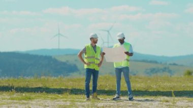 Kapatın işçiler el sıkışıyor ek yel değirmenlerini tartışıyorlar kurulum işi temiz enerji alanı enerji santrali jeneratörü rüzgar enerjisi türbinleri yavaş çekim