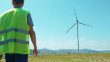Erkek mühendisler, tarlalarda yel değirmenlerinin yanında dizüstü bilgisayar standı kullanırlar. Ekip, iş birliği, rüzgar enerjisi, tarım teknisyenleri, yavaş çekim konuşmaları yaparlar.