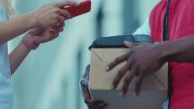 Genç Afrikalı Amerikalı kurye teslimat servisi posta kutusunu internetten alıyor. Nakliye siparişi ile ödeme yapıyor. Perakende satış paketi karantina alışverişi yapıyor.