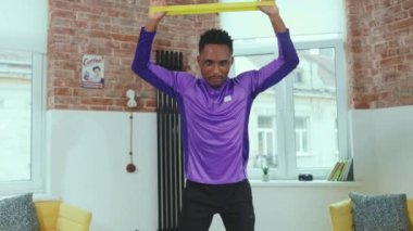Yakışıklı Afrikalı Amerikalı adam evde dizüstü bilgisayar kullanarak spor salonunda spor yapmak için lastik bant kullanıyor spor kıyafetleri spor kıyafeti spor salonu aktivitesi yavaş çekim