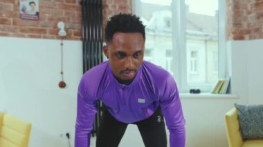 Genç Çekici Afrikalı Amerikalı adam evde dizüstü bilgisayar kullanarak spor salonunda spor için lastik bantlar kullanıyor spor kıyafetleri spor kıyafeti spor aktivitesi yavaş çekim
