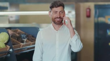 Portre genç adam telefonda konuşuyor. Sebze seçiyor. Müşteri seçiyor.