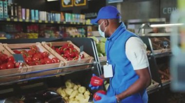 NEW YORK - 19 Nisan 2020: Genç Afro-Amerikan satışları eldiven giyer ve süpermarkette çalışan maske danışmanlığı yapar.