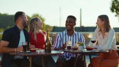 Gün ışığında mutlu arkadaşlar buluşur ve kokteyllerini içerler sokak kafesinde gülümserler hafta sonu şehir partileri arkadaşlığı şenlikleri yavaş çekim konuşmaları.
