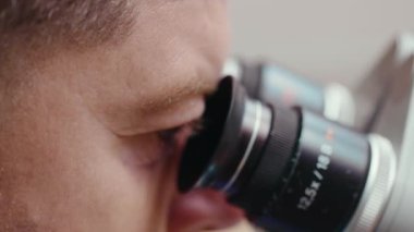 Diş mikroskobu ekipmanlarına bakan yüz doktoru. Sağlık eczanesi ekipmanları. Gözler yavaş çekimde.