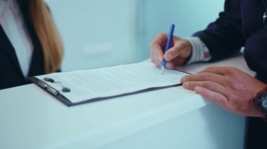 Ellerinizi kapatın. Klinikteki resepsiyonda formu doldurun. Belge tescil, tıbbi sağlık hizmetleri, erkek hasta tedavi hizmetleri, yavaş çekimde konuşma.