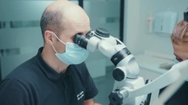 NEW YORK - 5 Nisan 2020: Tıbbi klinik stomatolojisi uzmanlık alanı ağız sağlığı diş hijyeni ağır çekimde asistanı ve müşterisi olan portre dişçisi