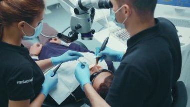 NEW YORK - 5 Nisan 2020: Tıbbi klinik stomatoloji uzmanlık alanı diş hijyeni yavaş çekim uzmanı asistanı ve müşterisi olarak dişçiyi sırtından vurdu