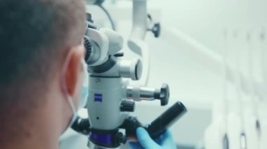 NEW YORK - 5 Nisan 2020: Tıbbi klinik stomatoloji uzmanı ağız sağlığı uzmanı diş hijyeni yavaş laboratuarında asistanı ve müşterisi olarak diş mikroskobuyla diş hekiminin fotoğrafı