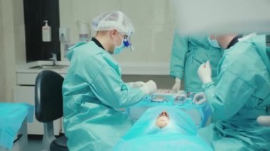 Diş hekimi koruyucu giysi ve eldiven giyer. Hasta diş cerrahisinde takım çalışması, tıbbi hijyenik hastalık hijyeni, yavaş çekim.