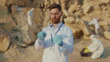 Genç adam ekoloji uzmanı korunma için şeffaf ekran tableti kullanıyor. Arazi yardım kimyasalları üzerinde çalışan gözlük takıyor. Toprak kirliliği.