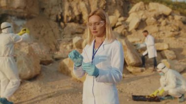 Ciddi kadın ekoloji uzmanı korunma için şeffaf ekran tableti kullanıyor. Arazi yardım kimyasalları üzerinde çalışan gözlük takıyor. Toprak kirliliği.