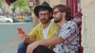 Komik eşcinsel çift dışarıda takılıyor telefonda gülümsüyor romantik bir ilişki kullanıyor yaz güneşli aşk sevgilileri buluşmaları gözlük konuşmaları homoseksüel yavaş çekim konuşmaları