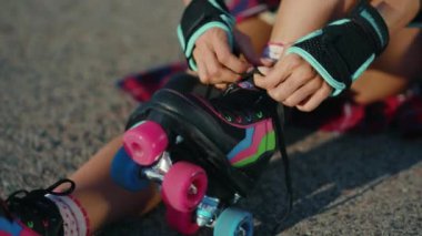 Ayaklarınızı ve ellerinizi kapatın genç bayan yerde oturuyor ve yazın gülümseyen caddelerde patenleri sürüyor bacaklar ağır çekimde patenle kayıyor